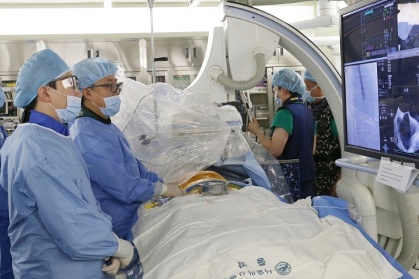 AMC Professor Park Duk-woo(second from left) performs the country's first MitraClip procedure as Professor Kim Dae-hee uses the echocardiography to determine the catheter's location in real time.Photo source: AMC
