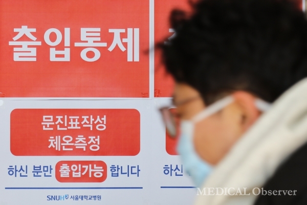 지난해 2월 서울대병원 본관 정문에 출입통제 안내문이 붙어있는 가운데 마스크를 쓴 방문객이 지나가고 있다. ⓒ메디칼업저버 김민수 기자