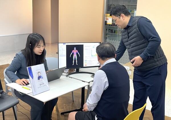 대웅제약 임직원(가운데)이 AI 근감소증 진단기기를 이용해 검사를 받은 후, 근감소증 유병 여부를 확인하고 있다.