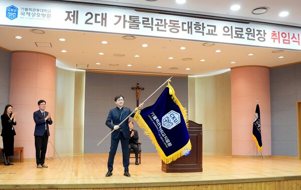 ▲가톨릭관동대 국제성모병원은 병원장 고동현 신부가 제2대 가톨릭관동대 의료원장으로 취임했다. 4일 국제성모병원 마리아홀에서 열린 신임 의료원장 취임식에서 고동현 신부는 의료원을 상징하는 의료원기를 전달받으며 가톨릭관동대 의료원장으로서 공식적인 첫 행보를 시작했다. 